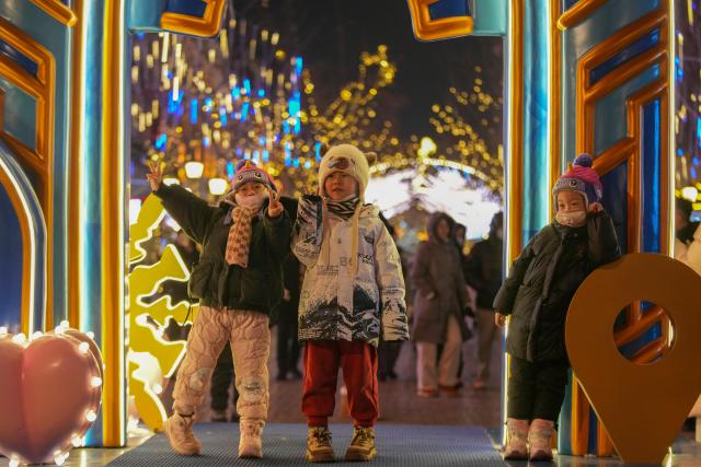 (260113) -- HARBIN, Jan. 13, 2026 (Xinhua) -- Children have fun on the Central Street in Harbin, northeast China's Heilongjiang Province, Jan. 11, 2026. As one of the most popular attractions in Harbin, the Central Street, which is renowned for its diverse European-style architecture, wows tourists with its colorful lights at night during the city's tourism boom this winter. (Xinhua/Wang Jianwei)