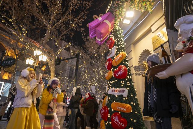 (260113) -- HARBIN, Jan. 13, 2026 (Xinhua) -- A woman poses for photos on the Central Street in Harbin, northeast China's Heilongjiang Province, Jan. 12, 2026. As one of the most popular attractions in Harbin, the Central Street, which is renowned for its diverse European-style architecture, wows tourists with its colorful lights at night during the city's tourism boom this winter. (Xinhua/Zhang Tao)