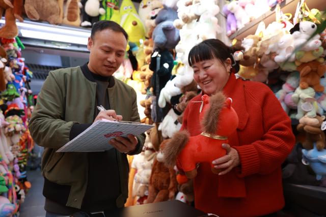 (260113) -- YIWU, Jan. 13, 2026 (Xinhua) -- Zhang Huoqing, general manager of plush toy store Happy Sister, checks orders at the Yiwu International Trade City in Yiwu, east China's Zhejiang Province, Jan. 10, 2026. TO GO WITH "China Focus: Even sad mascots sell: Yiwu toys riding the wave ahead of China's year of horse" (Xinhua)