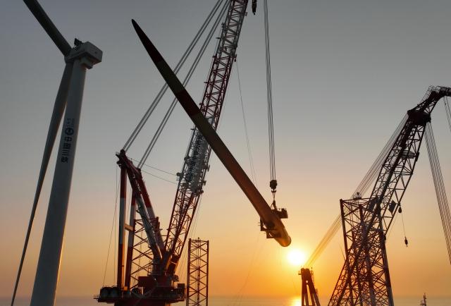 (260113) -- ZHANGZHOU, Jan. 13, 2026 (Xinhua) -- This drone photo taken on Jan. 13, 2026 shows one of the turbine blades being hoisted at the construction site of a 20-megawatt offshore wind turbine unit in the coastal waters of southeast China's Fujian Province. The wind turbine unit was successfully hoisted and installed here on Tuesday. (Xinhua/Lin Shanchuan)