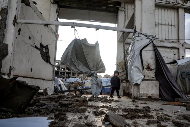 (260113) -- GAZA, Jan. 13, 2026 (Xinhua) -- A Palestinian child passes under a collapsed building due to the storm in Gaza City, Jan. 13, 2026. Four Palestinians were killed in Gaza City in two separate incidents, as heavy rain and strong winds swept the region on Tuesday. (Photo by Rizek Abdeljawad/Xinhua)