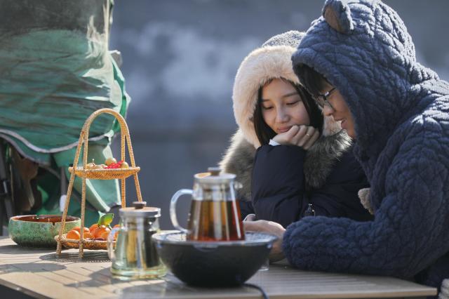 (260114) -- BEIJING, Jan. 14, 2026 (Xinhua) -- This photo taken on Jan. 7, 2026 shows tourists enjoying tea time at an outdoor tea house in Jiaxing City, east China's Zhejiang Province.
  China enters its coldest season in the eleventh month of the Chinese lunar calendar. 
  Urbanization and modern agriculture have weakened the impact of solar terms on daily life, but cultural and dietary habits have been passed down from generation to generation. (Photo by Jin Peng/Xinhua)