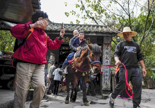(260114) -- PU'ER, Jan. 14, 2026 (Xinhua) -- Tourists ride a horse in Nakeli Village, in Hani and Yi Autonomous County of Ning'er, Pu'er City, southwest China's Yunnan Province on Jan. 14, 2026. The village of Nakeli, previously witnessed boisterous camel caravans carrying sacks of tea leaves while winding through ancient China's vast western area all the way to Southeast Asia and the Middle East. Today, the village has become a popular winter travel destination for tourists, thanks to its unique Tea Horse Road culture and pleasant climate. Besides visiting historical sites, tourists can also immerse themselves in activities such as making Pu'er tea products, retracing ancient paths on horseback, and tasting intangible cultural heritage cuisine. (Xinhua/Chen Xinbo)