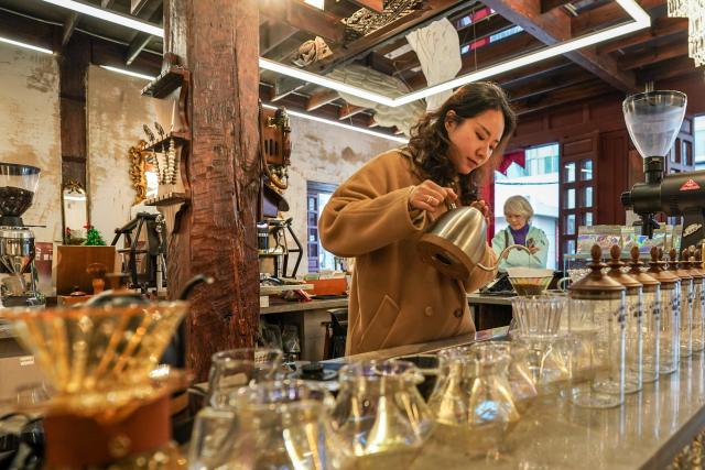 (260114) -- KUNMING, Jan. 14, 2026 (Xinhua) -- A staff member makes coffee for customers at a century-old coffee shop near Cuihu Lake in Kunming, southwest China's Yunnan Province, Jan. 13, 2026. Cuihu Lake is both a signature landscape of Kunming and a testament to the city's memories, surrounded by historical legacies such as the former sites of the National Southwestern Associated University and Yunnan Military Academy.
   Much like other older urban neighborhoods, the vicinity of Cuihu Lake had grappled with diminishing business vitality. The pressing challenge lies in revitalizing these dormant streets while preserving their historical essence and avoiding extensive demolition and construction.
   In recent years, a "cultural corridor" has been created around the lake, linking scattered historical and cultural sites while capitalizing on the thriving coffee industry. Cafe-centered boutique retail businesses have been established along this corridor, shaping an inclusive public space where people can feel free to take a walk, enjoy coffee and immerse themselves in reading. This endeavor has successfully infused the old neighborhoods with new waves of consumption. "Going to the Cuihu Lake for coffee" is now trending among local residents and tourists alike. (Xinhua/Peng Yikai)