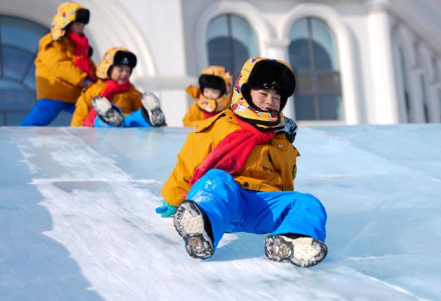 (260115) -- CHANGCHUN, Jan. 15, 2026 (Xinhua) -- Children play at an ice-and-snow themed park in Changchun, northeast China's Jilin Province, Jan. 14, 2026.
  A group of preschool children, bundled up in bright orange down coats, has embarked on a trip to northeast China, a region renowned as a snowy wonderland in winter. They came from south China's Guangxi Zhuang Autonomous Region, over 3,000 km away, with a daytime temperature currently above 20 degrees Celsius. 
  As Guangxi is closely linked with sugar oranges, which has a peel color exactly the same as the down jackets worn by the children, these little intrepid travelers have been affectionately referred to as "little sugar oranges" by online communities. Wherever they go, they set off a craze on cyberspace and have accumulated a flood of followers curious about their adventure in the north. (Xinhua/Yan Linyun)
