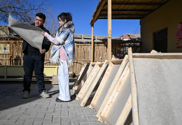 (260115) -- MOYU, Jan. 15, 2026 (Xinhua) -- Muyassar Ahmattohti (R) communicates with Bilal, a county-level representative inheritor of mulberry paper making skills, at a mulberry paper industrial park in Moyu County, northwest China's Xinjiang Uygur Autonomous Region, on Jan. 14, 2026. Muyassar Ahmattohti, who graduated from Xinjiang Arts University in 2025, returned to her hometown and became a designer of cultural and creative products of mulberry paper, a national intangible cultural heritage with a history of over a thousand years.
   A mulberry paper cultural industrial park was built and put into operation in Moyu County in 2025, which integrates cultural display, creative incubation and tourism, providing a brand-new platform for the inheritance of mulberry paper. 
   In the industrial park, Muyassar has her own space for creation on mulberry paper, and meanwhile, by shooting short videos and other means, she is able to bring the mulberry paper into the view of more people.
   Muyassar's design inspiration comes from the natural elements around her and the traditional culture of her hometown. In her hands, this ancient craftsmanship is no longer staying silent but has been transformed into wearable patterns, light installations, and other companions for people. 
   "Every time the brush touches the mulberry paper, I can feel that I have connected the past and future of my hometown," said Muyassar. (Xinhua/Ding Lei)
