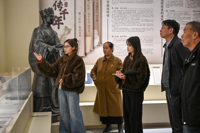 (260115) -- MOYU, Jan. 15, 2026 (Xinhua) -- Muyassar Ahmattohti (3rd R) listens to the introduction of a docent at an exhibition hall of a mulberry paper industrial park in Moyu County, northwest China's Xinjiang Uygur Autonomous Region, on Jan. 12, 2026. Muyassar Ahmattohti, who graduated from Xinjiang Arts University in 2025, returned to her hometown and became a designer of cultural and creative products of mulberry paper, a national intangible cultural heritage with a history of over a thousand years.
   A mulberry paper cultural industrial park was built and put into operation in Moyu County in 2025, which integrates cultural display, creative incubation and tourism, providing a brand-new platform for the inheritance of mulberry paper. 
   In the industrial park, Muyassar has her own space for creation on mulberry paper, and meanwhile, by shooting short videos and other means, she is able to bring the mulberry paper into the view of more people.
   Muyassar's design inspiration comes from the natural elements around her and the traditional culture of her hometown. In her hands, this ancient craftsmanship is no longer staying silent but has been transformed into wearable patterns, light installations, and other companions for people. 
   "Every time the brush touches the mulberry paper, I can feel that I have connected the past and future of my hometown," said Muyassar. (Xinhua/Ding Lei)