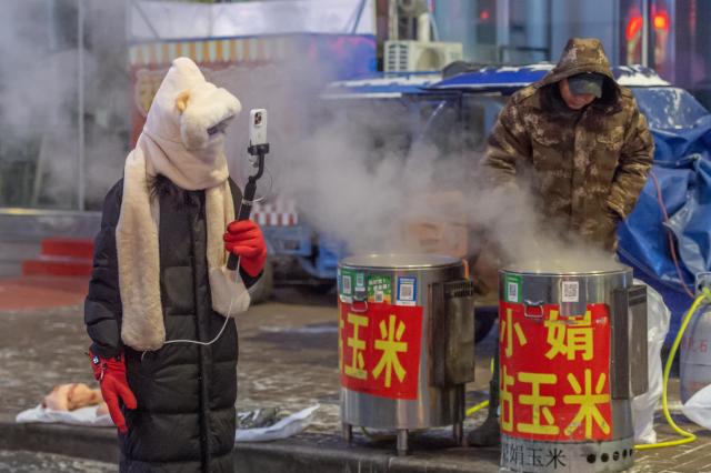 (260115) -- HARBIN, Jan. 15, 2026 (Xinhua) -- A live streamer is seen at a morning market in Qiqihar, northeast China's Heilongjiang Province, Jan. 14, 2026. In winter, morning markets across Heilongjiang would open amid temperatures reaching minus 20 or even 30 degrees Celsius. Local residents and tourists stroll amid the stalls, where steam would rise among the cold air. (Photo by Wang Yonggang/Xinhua)