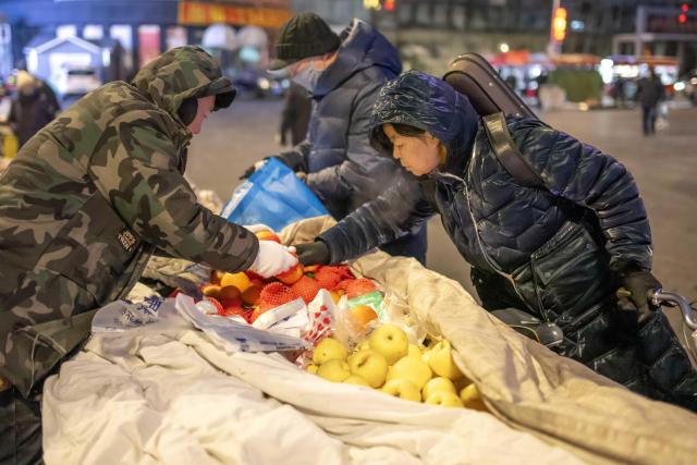 (260115) -- HARBIN, Jan. 15, 2026 (Xinhua) -- Citizens select fruits covered by cotton-padded quilts at a morning market in Qiqihar, northeast China's Heilongjiang Province, Jan. 14, 2026. In winter, morning markets across Heilongjiang would open amid temperatures reaching minus 20 or even 30 degrees Celsius. Local residents and tourists stroll amid the stalls, where steam would rise among the cold air. (Photo by Wang Yonggang/Xinhua)