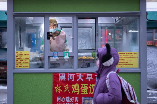 (260115) -- HARBIN, Jan. 15, 2026 (Xinhua) -- A breakfast stall with Russian menu is seen at a morning market in Heihe, northeast China's Heilongjiang Province, Jan. 14, 2026. In winter, morning markets across Heilongjiang would open amid temperatures reaching minus 20 or even 30 degrees Celsius. Local residents and tourists stroll amid the stalls, where steam would rise among the cold air. (Photo by Zhao Donglai/Xinhua)