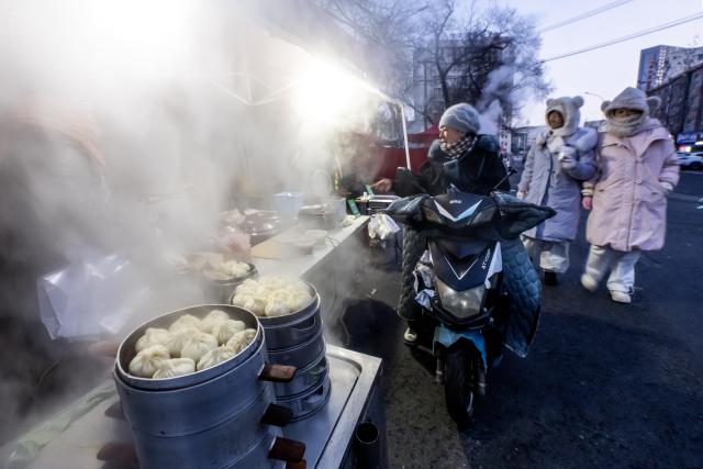 (260115) -- HARBIN, Jan. 15, 2026 (Xinhua) -- Citizens buy steamed buns at a morning market in Qiqihar, northeast China's Heilongjiang Province, Jan. 15, 2026. In winter, morning markets across Heilongjiang would open amid temperatures reaching minus 20 or even 30 degrees Celsius. Local residents and tourists stroll amid the stalls, where steam would rise among the cold air. (Photo by Wang Yonggang/Xinhua)
