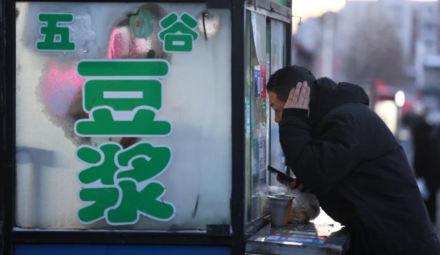 (260115) -- HARBIN, Jan. 15, 2026 (Xinhua) -- A customer buys soy milk at a morning market in Harbin, northeast China's Heilongjiang Province, Jan. 14, 2026. In winter, morning markets across Heilongjiang would open amid temperatures reaching minus 20 or even 30 degrees Celsius. Local residents and tourists stroll amid the stalls, where steam would rise among the cold air. (Photo by Zhang Shu/Xinhua)