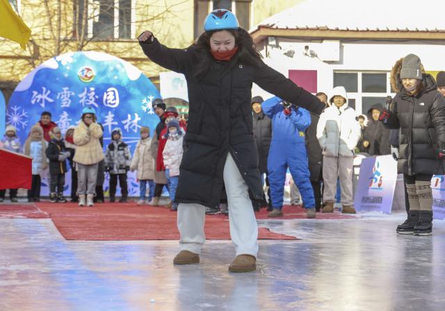(260115) -- BEIJING, Jan. 15, 2026 (Xinhua) -- People take part in an ice-sliding game at an elementary school in Yichun City, northeast China's Heilongjiang Province, Jan. 15, 2026. (Photo by Li Jiaxing/Xinhua)