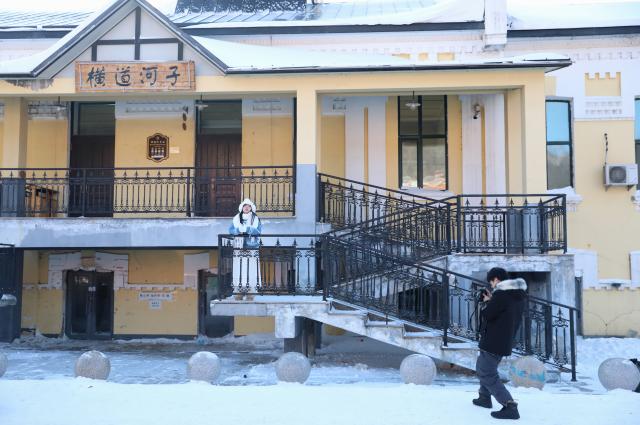 (260115) -- HAILIN, Jan. 15, 2026 (Xinhua) -- Tourists take photos in Hengdaohezi Town of Hailin City, northeast China's Heilongjiang Province, Jan. 15, 2025. Dubbed "a town pulled by trains," Hengdaohezi was originally established in the late 19th century when Russians built train maintenance workshops and other facilities there following the construction of the Chinese Eastern Railway. Due to well-preserved historic buildings, the exotic town now has become a popular tourist destination. (Xinhua/Yang Zhe)