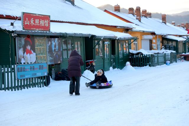 (260115) -- HAILIN, Jan. 15, 2026 (Xinhua) -- A child experiences snow tubing in Hengdaohezi Town of Hailin City, northeast China's Heilongjiang Province, Jan. 15, 2025. Dubbed "a town pulled by trains," Hengdaohezi was originally established in the late 19th century when Russians built train maintenance workshops and other facilities there following the construction of the Chinese Eastern Railway. Due to well-preserved historic buildings, the exotic town now has become a popular tourist destination. (Xinhua/Yang Zhe)