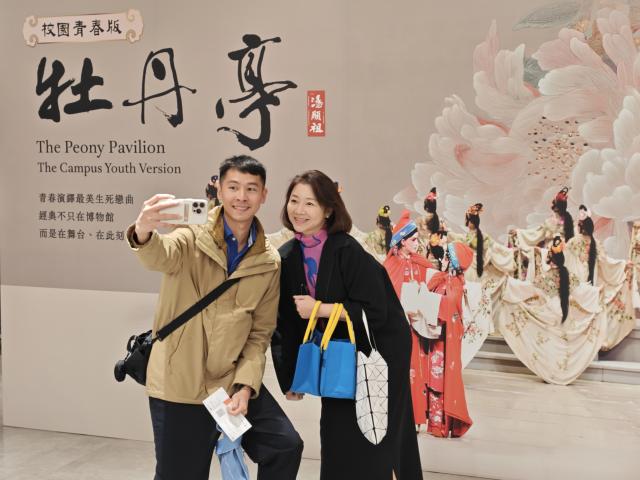 (260115) -- TAIPEI, Jan. 15, 2026 (Xinhua) -- Audience take a selfie in front of a poster of a campus youth version of the Kunqu Opera masterpiece "The Peony Pavilion" in Taipei, southeast China's Taiwan, Jan. 15, 2026. TO GO WITH "Mainland college students present Kunqu classic 'The Peony Pavilion' in Taipei" (Xinhua/Wang Chenghao)