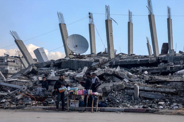 (260115) -- GAZA, Jan. 15, 2026 (Xinhua) -- Photo taken on Jan. 15, 2026 shows a vendor near damaged buildings in Gaza City. (Photo by Rizek Abdeljawad/Xinhua)