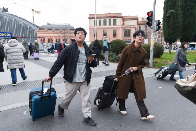(260116) -- MADRID, Jan. 16, 2026 (Xinhua) -- Two men walking with their luggage are pictured in Madrid, Spain, on Jan. 15, 2026. A total of 97 million foreign tourists visited Spain in 2025, setting a new all-time record for international visitors to the country, Spanish Minister of Industry and Tourism Jordi Hereu announced on Thursday. (Photo by Gustavo Valiente/Xinhua)