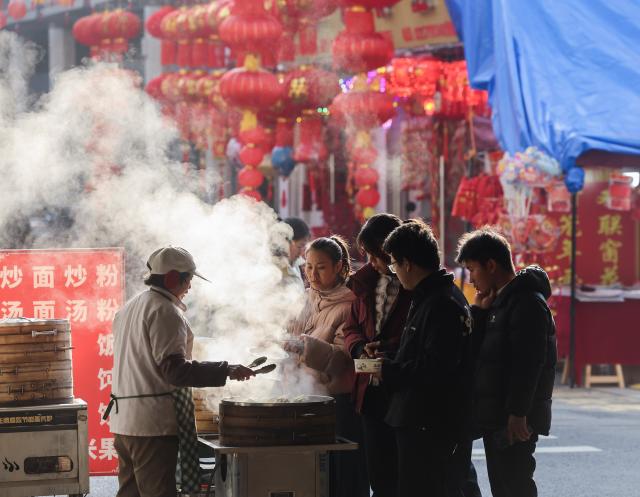 (260116) -- BEIJING, Jan. 16, 2026 (Xinhua) -- People buy food at a food stall during a new year's shopping festival in Jiande, east China's Zhejiang Province, Jan. 15, 2026. The new year's shopping festival, featuring agricultural products, local delicacies, local opera performances and folk parades, kicked off at a local market in Jiande on Thursday. (Xinhua/Xu Yu)