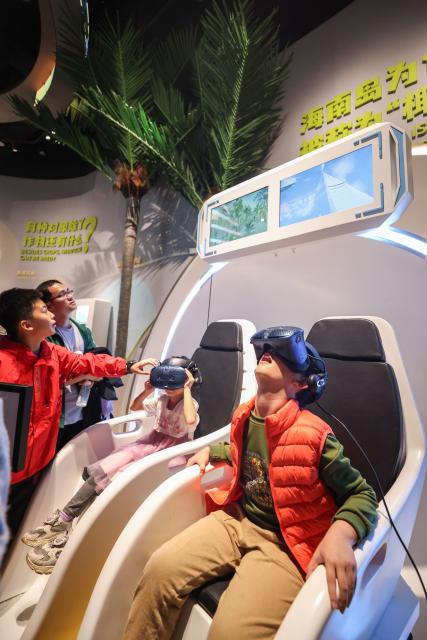 (260116) -- HAIKOU, Jan. 16, 2026 (Xinhua) -- People try VR devices at the Hainan Science and Technology Museum in Haikou, south China's Hainan Province, Jan. 15, 2026. The Hainan Science and Technology Museum has recently kicked off trial operation, drawing numerous families and science fans to explore the immersive and hands-on exhibits there.
   A brand-new landmark for science popularization in the Hainan Free Trade Port, the museum in a spiraling "auspicious cloud" design boasts a total construction area of approximately 46,500 square meters. It highlights Hainan's advantages in innovation, showcases local technological achievements, and reflects the integration of ecology and technology. (Xinhua/Zhang Liyun)