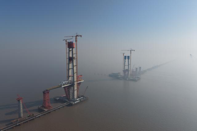 (260116) -- HAIYAN, Jan. 16, 2026 (Xinhua) -- A drone photo taken on Jan. 16, 2026 shows the topped-out No. 8 main tower (L) of the northern navigation channel bridge along the Hangzhou Bay Cross-Sea Railway Bridge in east China's Zhejiang Province. The 200-meter-high No. 8 main tower of the northern navigation channel bridge along the Hangzhou Bay Cross-Sea Railway Bridge was topped out on Friday.
   The 29.2-km-long Hangzhou Bay Cross-Sea Railway Bridge, which is a crucial segment of the Nantong-Suzhou-Jiaxing-Ningbo High Speed Railway, consists of three navigation channel bridges and 26-km-long approach bridges, and adopts a ballastless double-track design, with a designed top speed of 350 kilometers per hour. (Xinhua/Huang Zongzhi)
