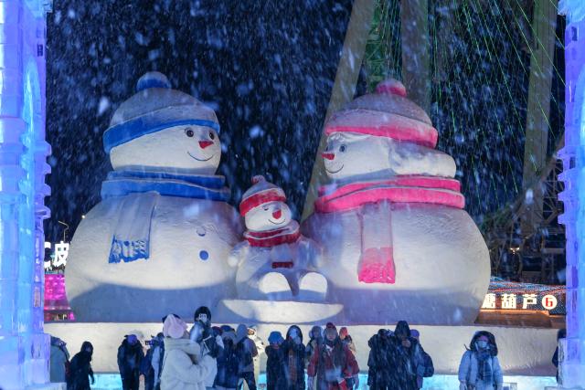 (260117) -- HARBIN, Jan. 17, 2026 (Xinhua) -- Tourists take photos near giant snowmen at the Harbin Ice-Snow World in Harbin, northeast China's Heilongjiang Province, Jan. 13, 2026. With the arrival of the ice and snow season, various public facilities in Heilongjiang Province have created distinctive snowman-themed landscapes to attract locals and tourists. (Xinhua/Wang Jianwei)
