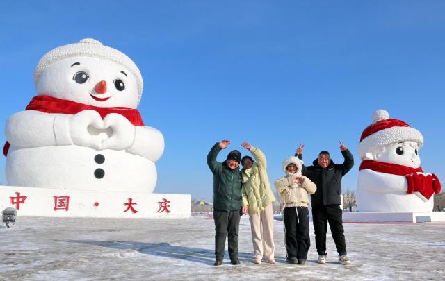 (260117) -- HARBIN, Jan. 17, 2026 (Xinhua) -- Tourists pose for photos with giant snowmen in Daqing City, northeast China's Heilongjiang Province, Jan. 16, 2026. With the arrival of the ice and snow season, various public facilities in Heilongjiang Province have created distinctive snowman-themed landscapes to attract locals and tourists. (Photo by Lu Wenxiang/Xinhua)