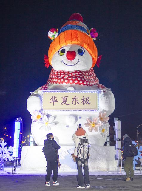 (260117) -- HARBIN, Jan. 17, 2026 (Xinhua) -- A tourist takes a photo of a giant snowman in Jiamusi City, northeast China's Heilongjiang Province, Jan. 15, 2026. With the arrival of the ice and snow season, various public facilities in Heilongjiang Province have created distinctive snowman-themed landscapes to attract locals and tourists. (Photo by Chen Zhiguo/Xinhua)