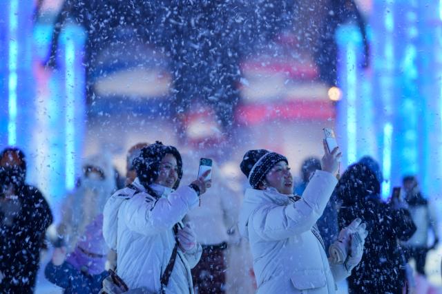 (260117) -- HARBIN, Jan. 17, 2026 (Xinhua) -- Tourists take photos near giant snowmen at the Harbin Ice-Snow World in Harbin, northeast China's Heilongjiang Province, Jan. 13, 2026. With the arrival of the ice and snow season, various public facilities in Heilongjiang Province have created distinctive snowman-themed landscapes to attract locals and tourists. (Xinhua/Wang Jianwei)