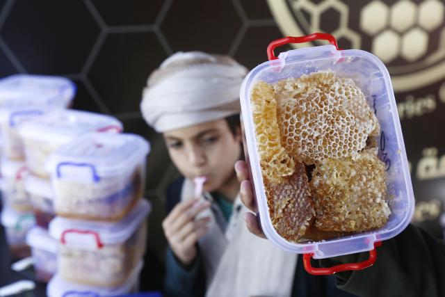 (260118) -- SANAA, Jan. 18, 2026 (Xinhua) -- A child tastes honey as his father buys some during the annual Yemeni honey festival in Sanaa, Yemen, on Jan. 17, 2026. The annual Yemeni honey festival themed "Yemen, the Home of Honey," was held in Sanaa on Saturday, aiming to uphold its status as one of the nation's most significant products, valued for its nutrition and economic benefits. (Photo by Mohammed Mohammed/Xinhua)