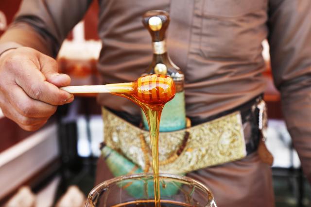 (260118) -- SANAA, Jan. 18, 2026 (Xinhua) -- A honey producer shows his product during the annual Yemeni honey festival in Sanaa, Yemen, on Jan. 17, 2026. The annual Yemeni honey festival themed "Yemen, the Home of Honey," was held in Sanaa on Saturday, aiming to uphold its status as one of the nation's most significant products, valued for its nutrition and economic benefits. (Photo by Mohammed Mohammed/Xinhua)
