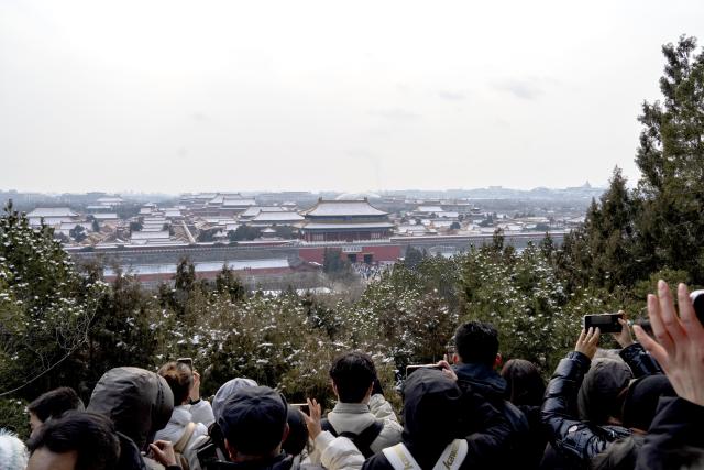 (260118) -- BEIJING, Jan. 18, 2026 (Xinhua) -- People take photos of the Palace Museum after a snowfall at the Jingshan Park in Beijing, capital of China, Jan. 18, 2026. Beijing witnessed a snowfall this weekend. (Xinhua/Xie Han)