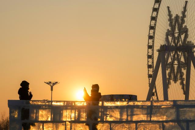 (260118) -- HARBIN, Jan. 18, 2026 (Xinhua) -- Tourists have fun at sunset at the Harbin Ice-Snow World, the world's largest ice-and-snow theme park, in Harbin, northeast China's Heilongjiang Province, Jan. 18, 2026. (Xinhua/Wang Jianwei)