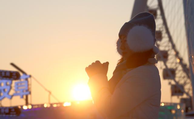 (260118) -- HARBIN, Jan. 18, 2026 (Xinhua) -- A tourist poses for photos at sunset at the Harbin Ice-Snow World, the world's largest ice-and-snow theme park, in Harbin, northeast China's Heilongjiang Province, Jan. 18, 2026. (Photo by Zhang Shu/Xinhua)