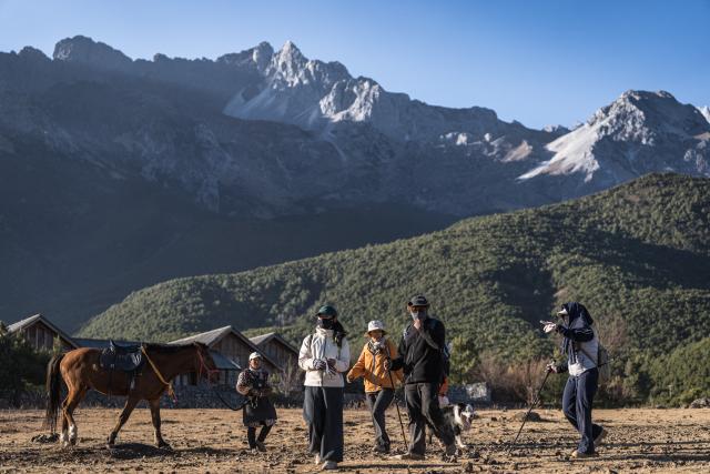 (260119) -- LIJIANG, Jan. 19, 2026 (Xinhua) -- Visitors hike in Yuhu Village, Lijiang City, southwest China's Yunnan Province, Jan. 17, 2026. Yuhu Village, nestled in Baisha Township of Yulong Naxi Autonomous County in the city of Lijiang in Yunnan, is one of the earliest settlements of the Naxi ethnic people. The village was once among the poorest villages in Lijiang because of its poor soil and limited transportation links.   
  In recent years, Yuhu has developed a distinct path that balances economic growth with environmental protection. Leveraging its well-preserved Naxi cultural heritage and exceptional natural scenery, the village has attracted visitors from around the world. At the same time, it has continued to improve infrastructure and public services, attracting a growing number of residents to return home for businesses.  
  In 2025, Yuhu Village welcomed about 1.2 million visits, generating 75 million yuan (10.8 million U.S. dollars) in revenue -- with the average income of locals increasing from 13,000 yuan (1,865 U.S. dollars) in 2019 to about 35,000 yuan (5,022 U.S. dollars). (Xinhua/Wang Guansen)
