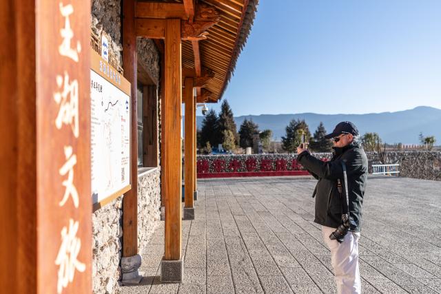 (260119) -- LIJIANG, Jan. 19, 2026 (Xinhua) -- A visitor takes photos at the visitor service center in Yuhu Village, Lijiang City, southwest China's Yunnan Province, Jan. 18, 2026. Yuhu Village, nestled in Baisha Township of Yulong Naxi Autonomous County in the city of Lijiang in Yunnan, is one of the earliest settlements of the Naxi ethnic people. The village was once among the poorest villages in Lijiang because of its poor soil and limited transportation links.   
  In recent years, Yuhu has developed a distinct path that balances economic growth with environmental protection. Leveraging its well-preserved Naxi cultural heritage and exceptional natural scenery, the village has attracted visitors from around the world. At the same time, it has continued to improve infrastructure and public services, attracting a growing number of residents to return home for businesses.  
  In 2025, Yuhu Village welcomed about 1.2 million visits, generating 75 million yuan (10.8 million U.S. dollars) in revenue -- with the average income of locals increasing from 13,000 yuan (1,865 U.S. dollars) in 2019 to about 35,000 yuan (5,022 U.S. dollars). (Xinhua/Gao Yongwei)