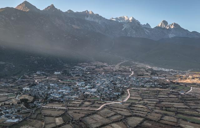(260119) -- LIJIANG, Jan. 19, 2026 (Xinhua) -- A drone photo taken from Yuhu Village shows a view of Yulong Snow Mountain, in Lijiang City, southwest China's Yunnan Province, Jan. 17, 2026. Yuhu Village, nestled in Baisha Township of Yulong Naxi Autonomous County in the city of Lijiang in Yunnan, is one of the earliest settlements of the Naxi ethnic people. The village was once among the poorest villages in Lijiang because of its poor soil and limited transportation links.   
  In recent years, Yuhu has developed a distinct path that balances economic growth with environmental protection. Leveraging its well-preserved Naxi cultural heritage and exceptional natural scenery, the village has attracted visitors from around the world. At the same time, it has continued to improve infrastructure and public services, attracting a growing number of residents to return home for businesses.  
  In 2025, Yuhu Village welcomed about 1.2 million visits, generating 75 million yuan (10.8 million U.S. dollars) in revenue -- with the average income of locals increasing from 13,000 yuan (1,865 U.S. dollars) in 2019 to about 35,000 yuan (5,022 U.S. dollars). (Xinhua/Wang Guansen)