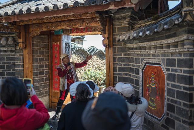 (260119) -- LIJIANG, Jan. 19, 2026 (Xinhua) -- A villager introduces the features of traditional Naxi architecture in Yuhu Village, Lijiang City, southwest China's Yunnan Province, Jan. 17, 2026. Yuhu Village, nestled in Baisha Township of Yulong Naxi Autonomous County in the city of Lijiang in Yunnan, is one of the earliest settlements of the Naxi ethnic people. The village was once among the poorest villages in Lijiang because of its poor soil and limited transportation links.   
  In recent years, Yuhu has developed a distinct path that balances economic growth with environmental protection. Leveraging its well-preserved Naxi cultural heritage and exceptional natural scenery, the village has attracted visitors from around the world. At the same time, it has continued to improve infrastructure and public services, attracting a growing number of residents to return home for businesses.  
  In 2025, Yuhu Village welcomed about 1.2 million visits, generating 75 million yuan (10.8 million U.S. dollars) in revenue -- with the average income of locals increasing from 13,000 yuan (1,865 U.S. dollars) in 2019 to about 35,000 yuan (5,022 U.S. dollars). (Xinhua/Wang Guansen)