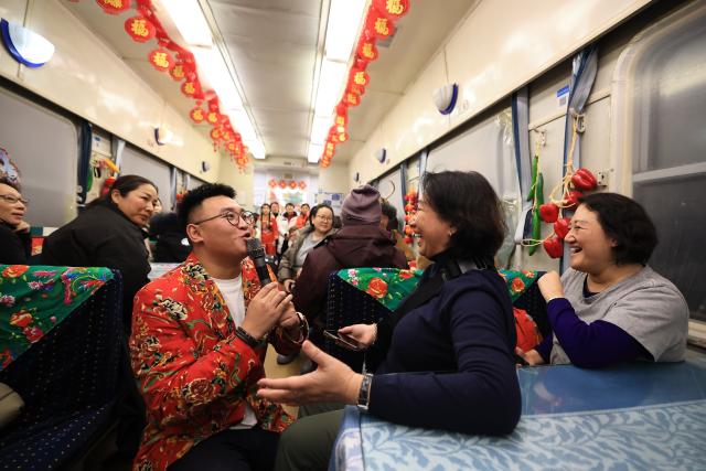 (260119) -- HARBIN, Jan. 19, 2026 (Xinhua) -- A tourist from Malaysia (2nd R) interacts with a staff member on K7041, a train themed on folk culture of northeast China, in northeast China's Heilongjiang Province, Jan. 19, 2026. Recently, tourists from Southeast Asian countries have been flocking to Harbin, hailed as China's "Ice City," with unprecedented enthusiasm. (Photo by Xu Shuai/Xinhua)