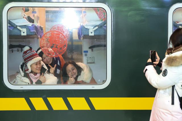 (260119) -- HARBIN, Jan. 19, 2026 (Xinhua) -- Foreign tourists pose for photos on K7041, a train themed on folk culture of northeast China, in northeast China's Heilongjiang Province, Jan. 19, 2026. Recently, tourists from Southeast Asian countries have been flocking to Harbin, hailed as China's "Ice City," with unprecedented enthusiasm. (Photo by Xu Shuai/Xinhua)