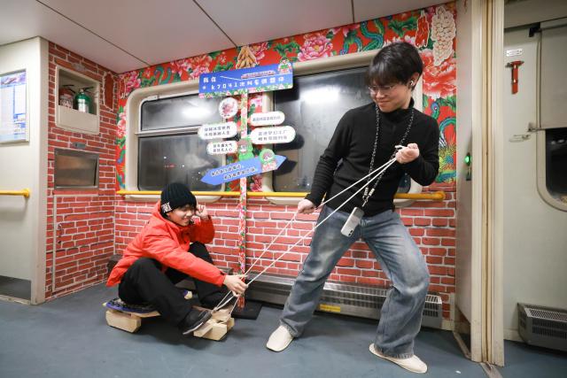 (260119) -- HARBIN, Jan. 19, 2026 (Xinhua) -- Foreign tourists experience a sledge on K7041, a train themed on folk culture of northeast China, in northeast China's Heilongjiang Province, Jan. 19, 2026. Recently, tourists from Southeast Asian countries have been flocking to Harbin, hailed as China's "Ice City," with unprecedented enthusiasm. (Photo by Xu Shuai/Xinhua)