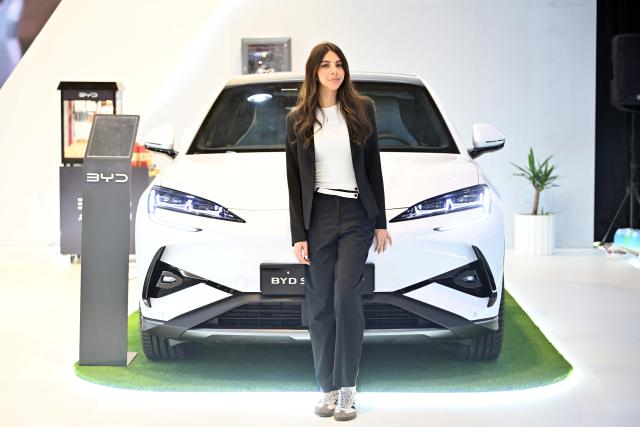 (260119) -- HAWALLI GOVERNORATE, Jan. 19, 2026 (Xinhua) -- A model takes a photo at the booth of Chinese car brand BYD during the Auto Show in Hawalli Governorate, Kuwait, Jan. 19, 2026. The Auto Show kicked off in Kuwait's Hawalli Governorate on Monday with the participation of more than 120 cars from around 30 car dealers showing 40 car brands. The event will last for 6 days from Jan. 19 to 24. (Photo by Asad/Xinhua)