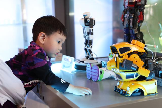 (260120) -- SHENZHEN, Jan. 20, 2026 (Xinhua) -- A child interacts with a robot at the world's first robot 6S store in Longgang District of Shenzhen, south China's Guangdong Province, on Jan. 16, 2026. Recently, a number of retail stores in tech sector opened in many business districts of Shenzhen. In theses tech stores, consumers can experience smart electronic products such as embodied intelligent robots, 3D printing, and smart glasses. Shenzhen, a city at the forefront of China's intelligent manufacturing, is creating new scenarios of immersive retail consumption, bringing cutting-edge technology to consumers. (Xinhua/Liang Xu)