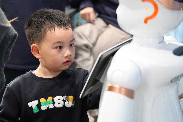 (260120) -- SHENZHEN, Jan. 20, 2026 (Xinhua) -- A child interacts with a robot at the world's first robot 6S store in Longgang District of Shenzhen, south China's Guangdong Province, on Jan. 16, 2026. Recently, a number of retail stores in tech sector opened in many business districts of Shenzhen. In theses tech stores, consumers can experience smart electronic products such as embodied intelligent robots, 3D printing, and smart glasses. Shenzhen, a city at the forefront of China's intelligent manufacturing, is creating new scenarios of immersive retail consumption, bringing cutting-edge technology to consumers. (Xinhua/Liang Xu)