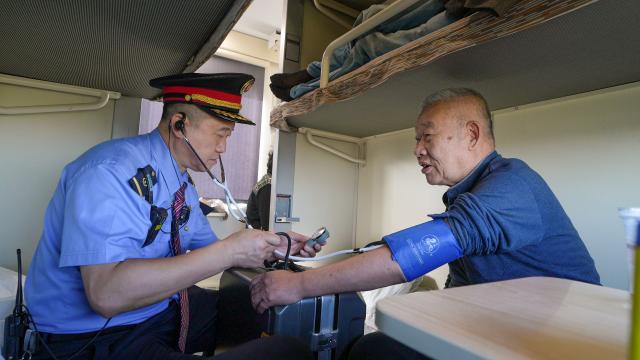(260120) -- HARBIN, Jan. 20, 2026 (Xinhua) -- Train conductor Wang Xijun measures blood pressure for an elderly passenger aboard the train Z114/Z111, fondly referred to as "the train of migratory birds," Nov. 26, 2025. TO GO WITH "Across China: 'Train of migratory birds' brings winter sunshine to elderly Chinese travelers" (Xinhua/Zhang Yue)