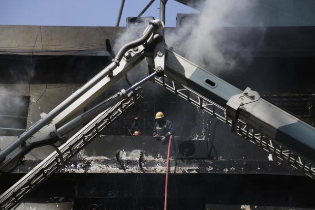 (260120) -- KARACHI, Jan. 20, 2026 (Xinhua) -- Rescuers work at the fire site at a shopping mall in southern Pakistani port city of Karachi on Jan. 20, 2026. The death toll from a massive fire at a multi-storey commercial building in Pakistan's southern port city of Karachi has risen to 26, while 74 people are still missing, officials said on Tuesday. (Str/Xinhua)