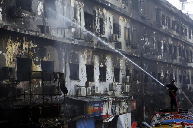 (260120) -- KARACHI, Jan. 20, 2026 (Xinhua) -- A rescuer tries to extinguish fire at the fire site at a shopping mall in southern Pakistani port city of Karachi on Jan. 20, 2026. The death toll from a massive fire at a multi-storey commercial building in Pakistan's southern port city of Karachi has risen to 26, while 74 people are still missing, officials said on Tuesday. (Str/Xinhua)
