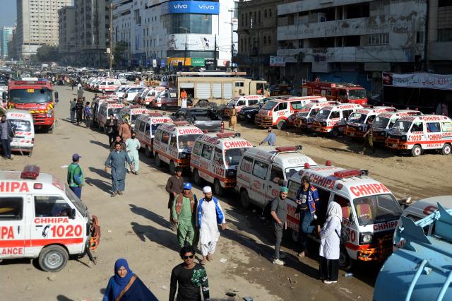 (260120) -- KARACHI, Jan. 20, 2026 (Xinhua) -- Ambulances are seen at the fire site at a shopping mall in southern Pakistani port city of Karachi on Jan. 20, 2026. The death toll from a massive fire at a multi-storey commercial building in Pakistan's southern port city of Karachi has risen to 26, while 74 people are still missing, officials said on Tuesday. (Str/Xinhua)