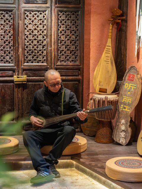 (260121) -- LIJIANG, Jan. 21, 2026 (Xinhua) -- He Dehua performs with a traditional instrument at the "Wayfarers" music club at the ancient city of Lijiang, southwest China's Yunnan Province, Jan. 17, 2026. He Dehua, 51, and his wife refurbished an old house of theirs in October 2025, and turned it into a music club called "Wayfarers," where they can share their personal stories with travelers and long-lost friends.
   The name "Wayfarers" came from a CD He had co-produced, drawing inspiration from his memory of watching elders of the family leaving hometown to work for livelihood. "We are all wayfarers in our own life, but we must not forget to search for the truth of life and the true self," said He.
   He has been a career musician for about three decades since he went to learn guitar playing in Beijing in 1997. Back to his hometown in Lijiang, he started to challenge himself by impressing the visitors to this olden city with music, songs and sounds of nature.
   He set out to collect voices and sounds in 2011, and has garnered more than 200 hours of recordings, which included some intangible cultural heritage items, voices in routine life, and melodies performed by folk artists. (Xinhua/Gao Yongwei)