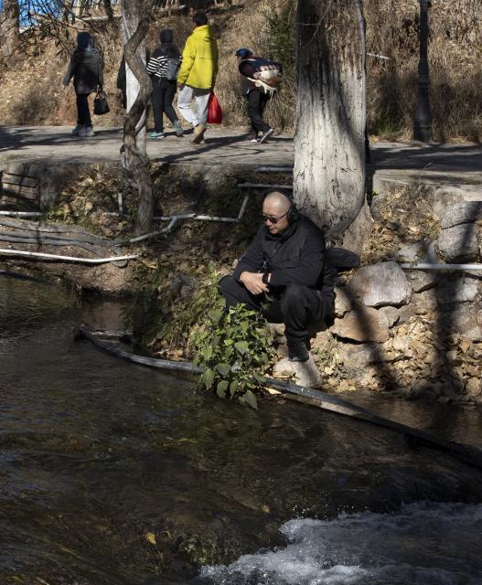 (260121) -- LIJIANG, Jan. 21, 2026 (Xinhua) -- He Dehua collects sounds beside the Yuhe River at the ancient city of Lijiang, southwest China's Yunnan Province, Jan. 16, 2026. He Dehua, 51, and his wife refurbished an old house of theirs in October 2025, and turned it into a music club called "Wayfarers," where they can share their personal stories with travelers and long-lost friends.
   The name "Wayfarers" came from a CD He had co-produced, drawing inspiration from his memory of watching elders of the family leaving hometown to work for livelihood. "We are all wayfarers in our own life, but we must not forget to search for the truth of life and the true self," said He.
   He has been a career musician for about three decades since he went to learn guitar playing in Beijing in 1997. Back to his hometown in Lijiang, he started to challenge himself by impressing the visitors to this olden city with music, songs and sounds of nature.
   He set out to collect voices and sounds in 2011, and has garnered more than 200 hours of recordings, which included some intangible cultural heritage items, voices in routine life, and melodies performed by folk artists. (Xinhua/Jiang Wenyao)